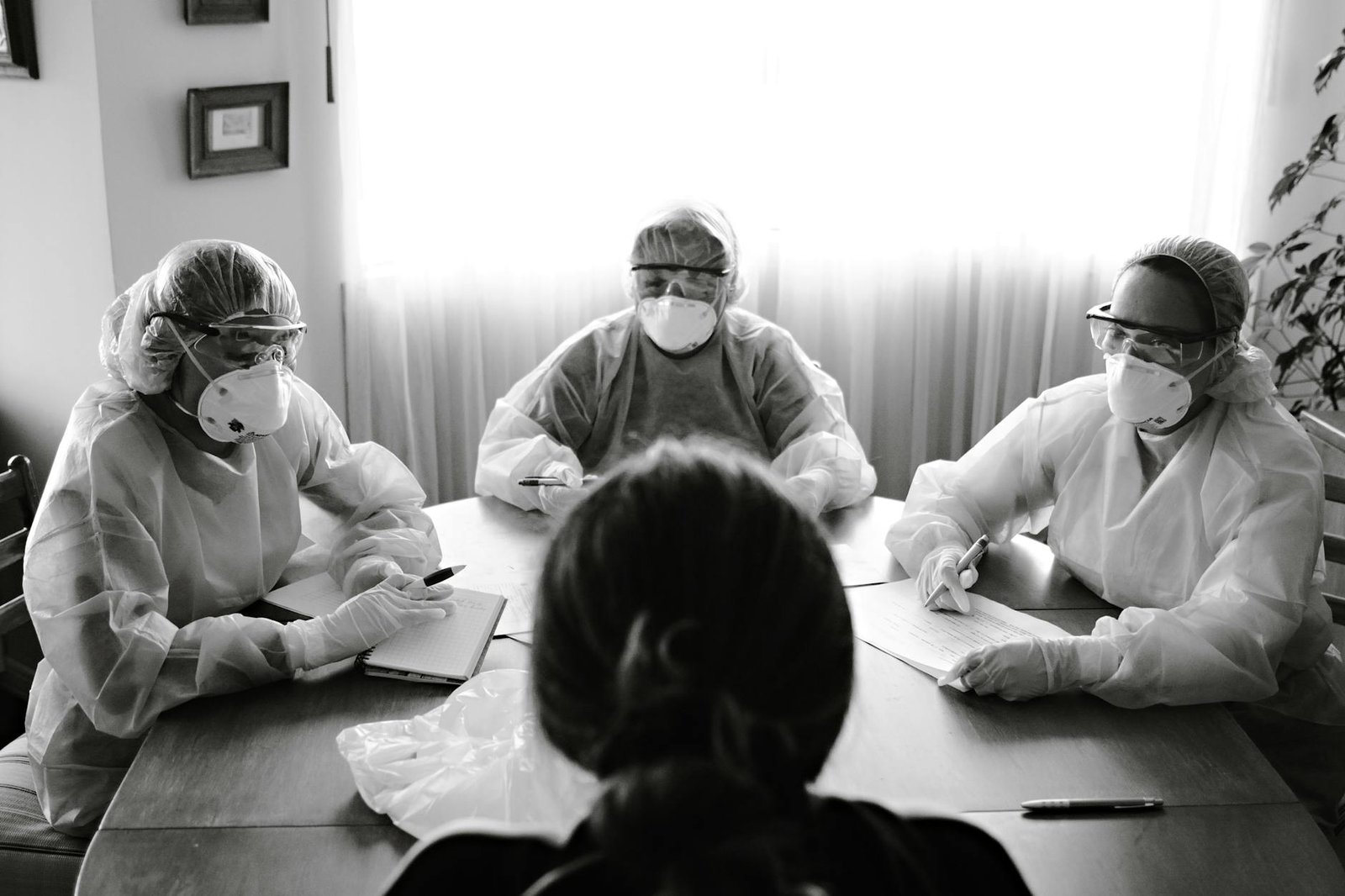 healthcare workers in protective gear at meeting table
