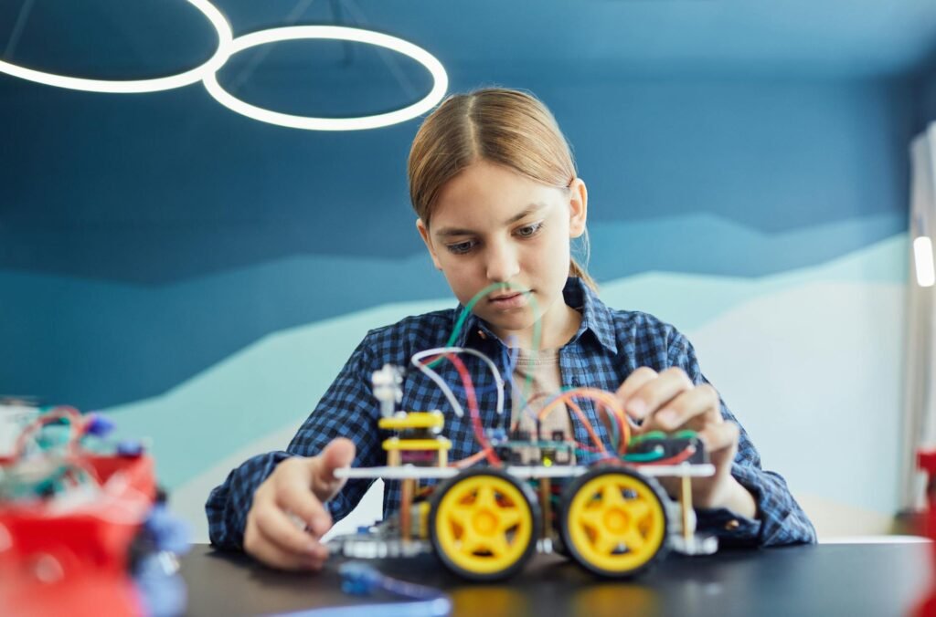 a girl looking at a wheeled toy with wires