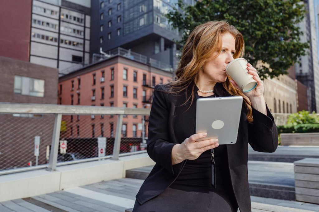 woman drinking coffee and holding a digital tablet