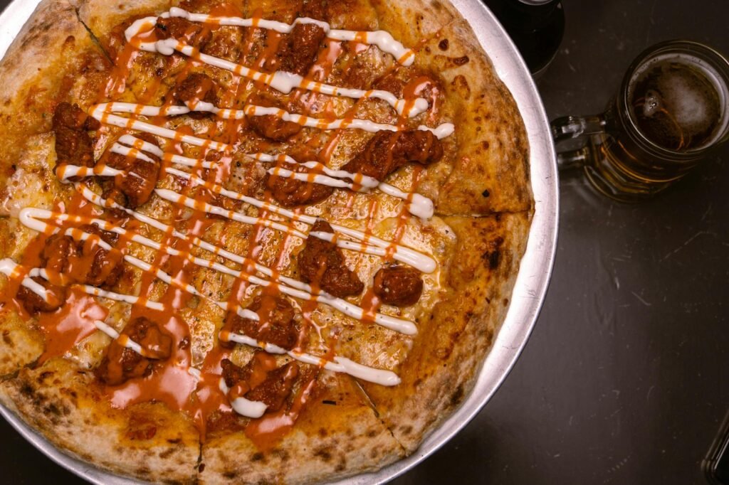 pizza with sauces and a glass of beer on a table