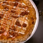 pizza with sauces and a glass of beer on a table