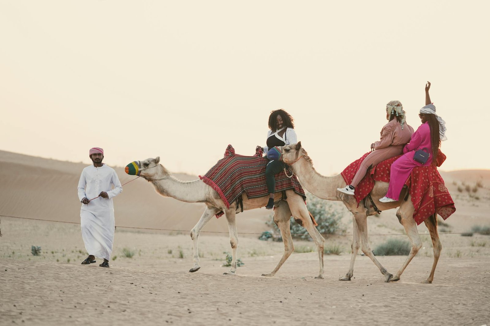 women riding camels on desert