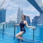 woman standing at pool with petronas twin towers behind in kuala lumpur