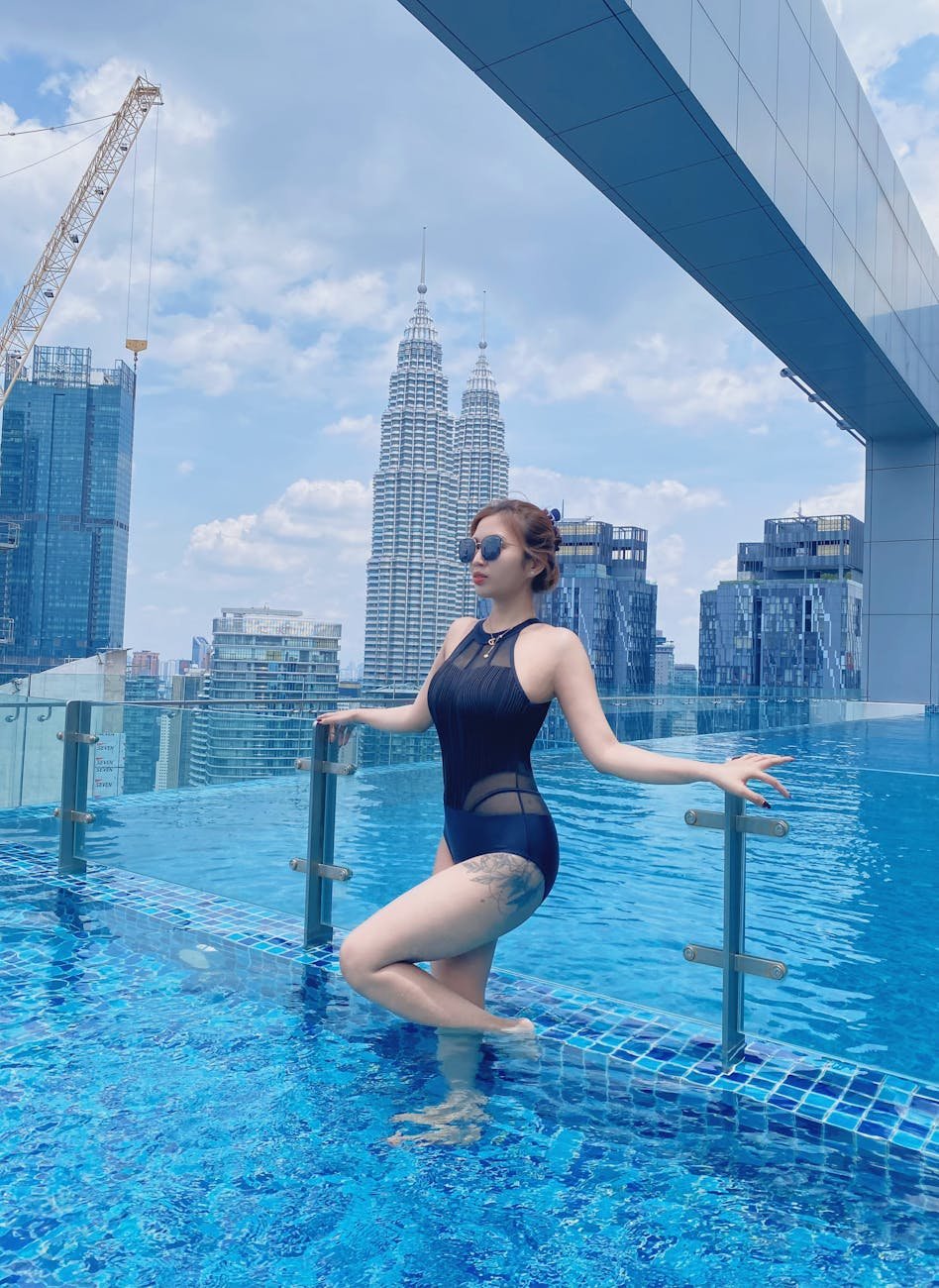 woman standing at pool with petronas twin towers behind in kuala lumpur