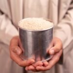 hands holding tin of rice in traditional clothes