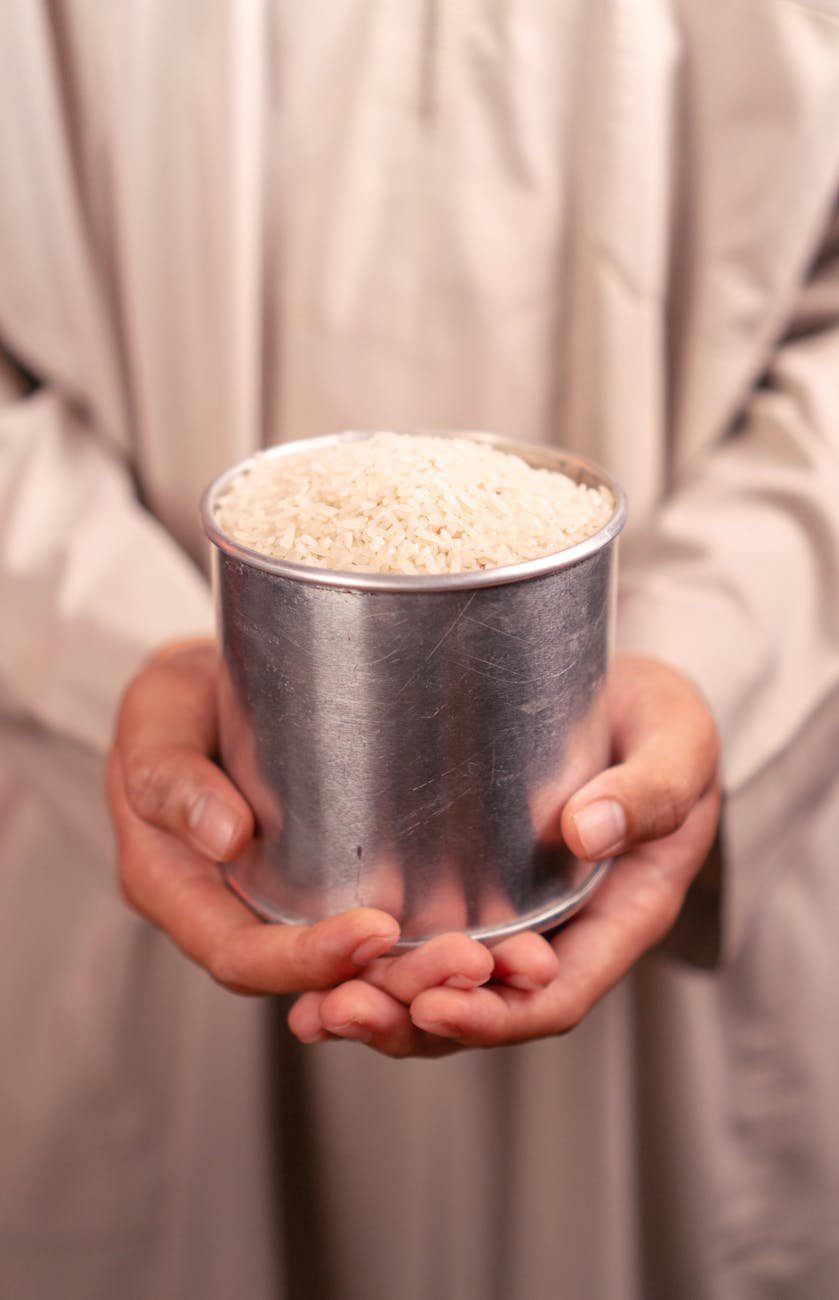 hands holding tin of rice in traditional clothes