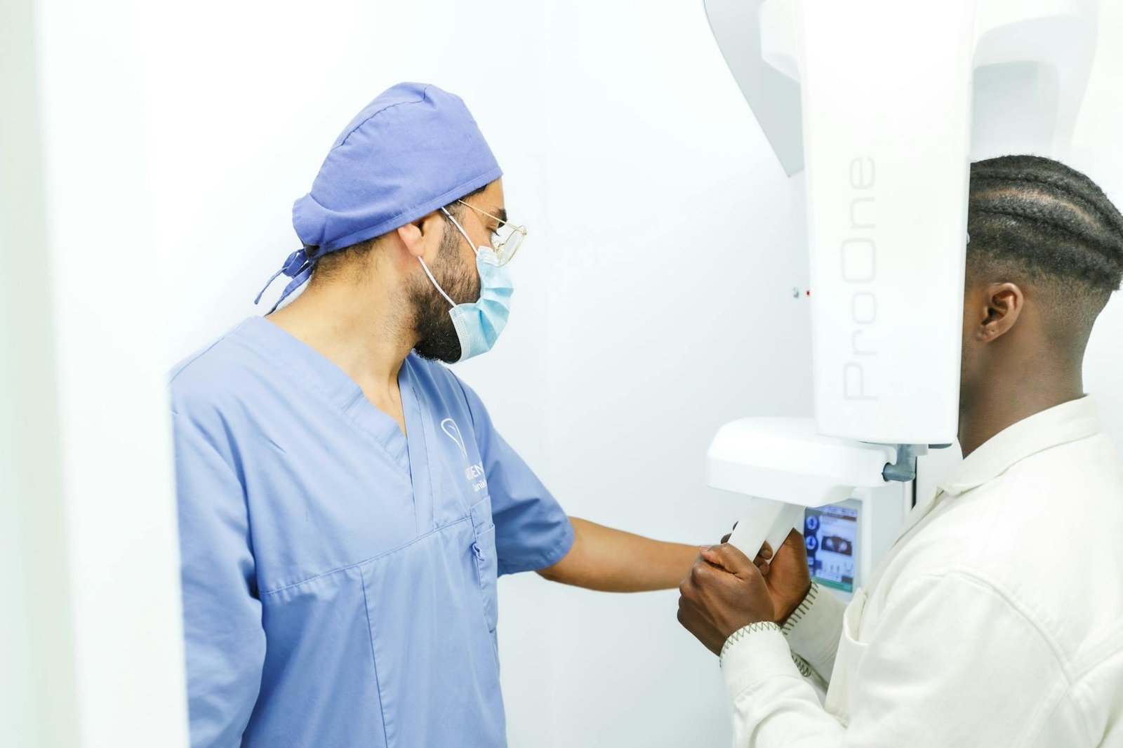 dentist assists patient with dental imaging machine