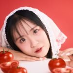 portrait of woman with tomatoes on red backdrop