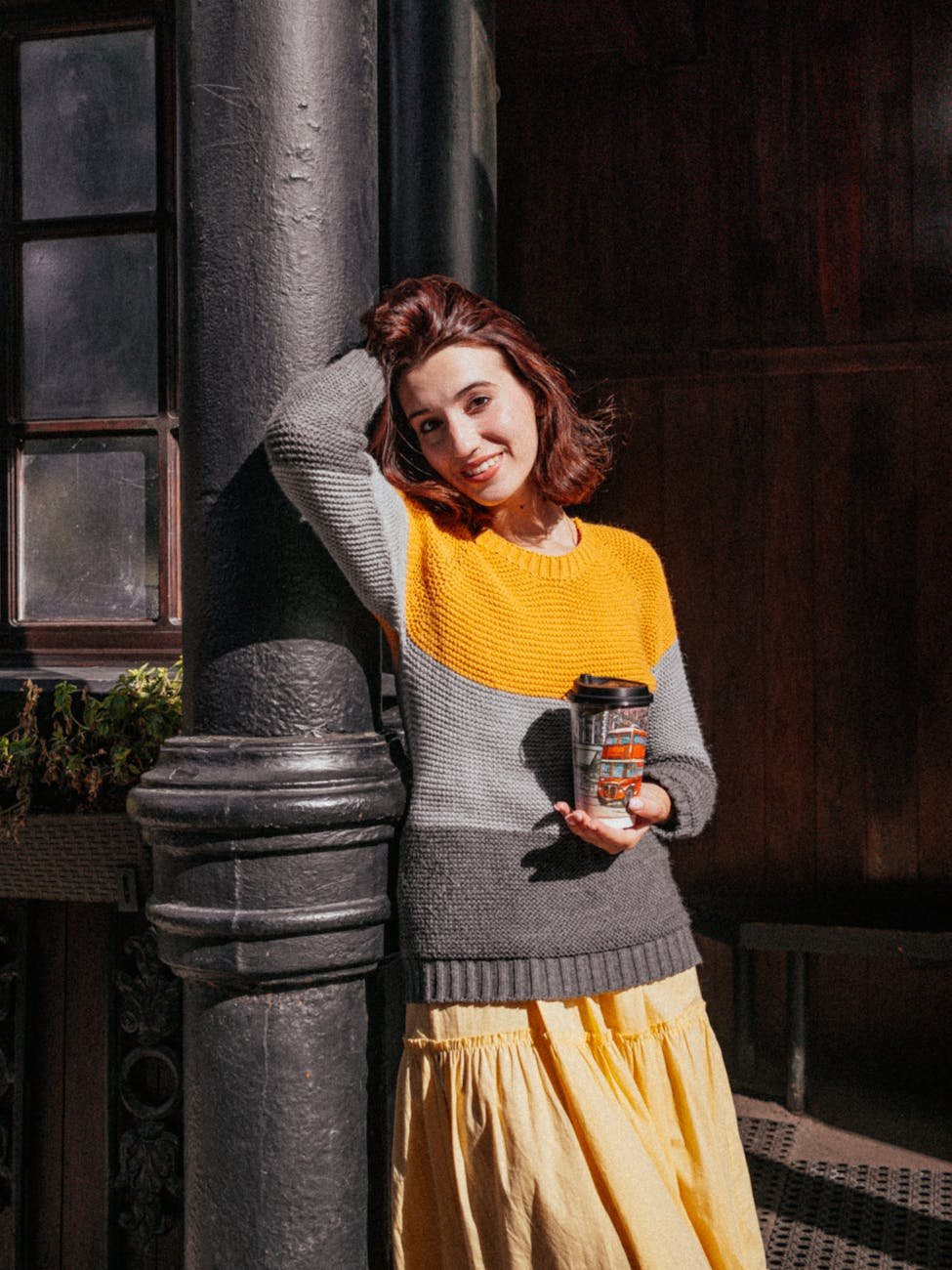 smiling woman in colorful sweater with coffee cup