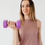 happy young sportswoman doing exercise with dumbbell