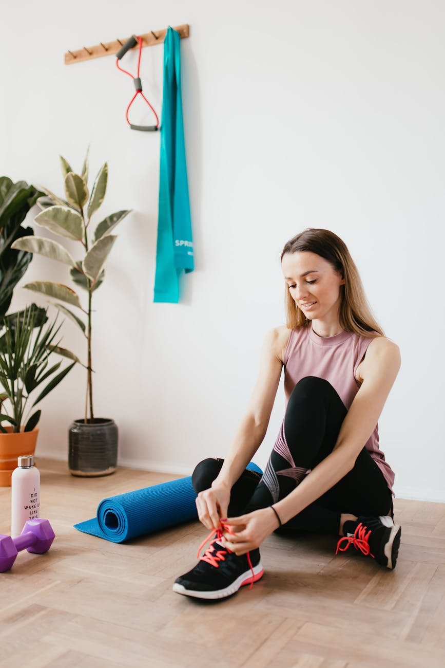 slim sportswoman tying sneakers before home workout