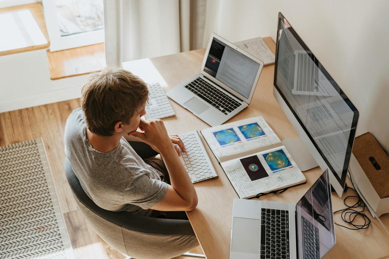 high angle shot of a boy sitting on grey chair while using his laptop computers