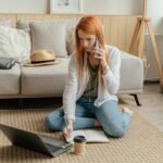 woman in white long sleeve shirt and blue denim jeans sitting on gray couch