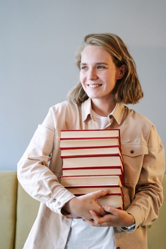 woman in beige blazer holding red book