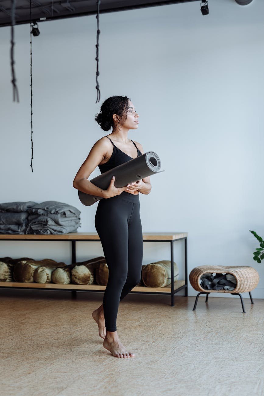 a woman in black tank top holding a yoga mat