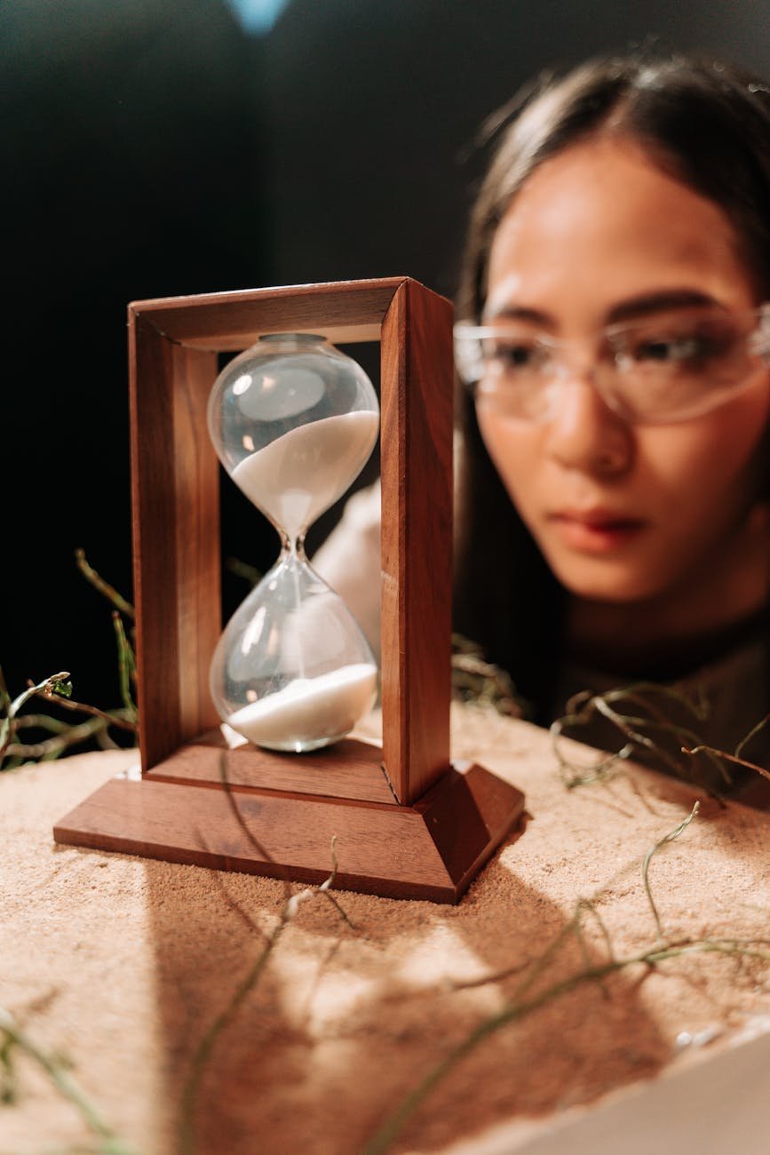 woman looking on a hourglass on wooden frame
