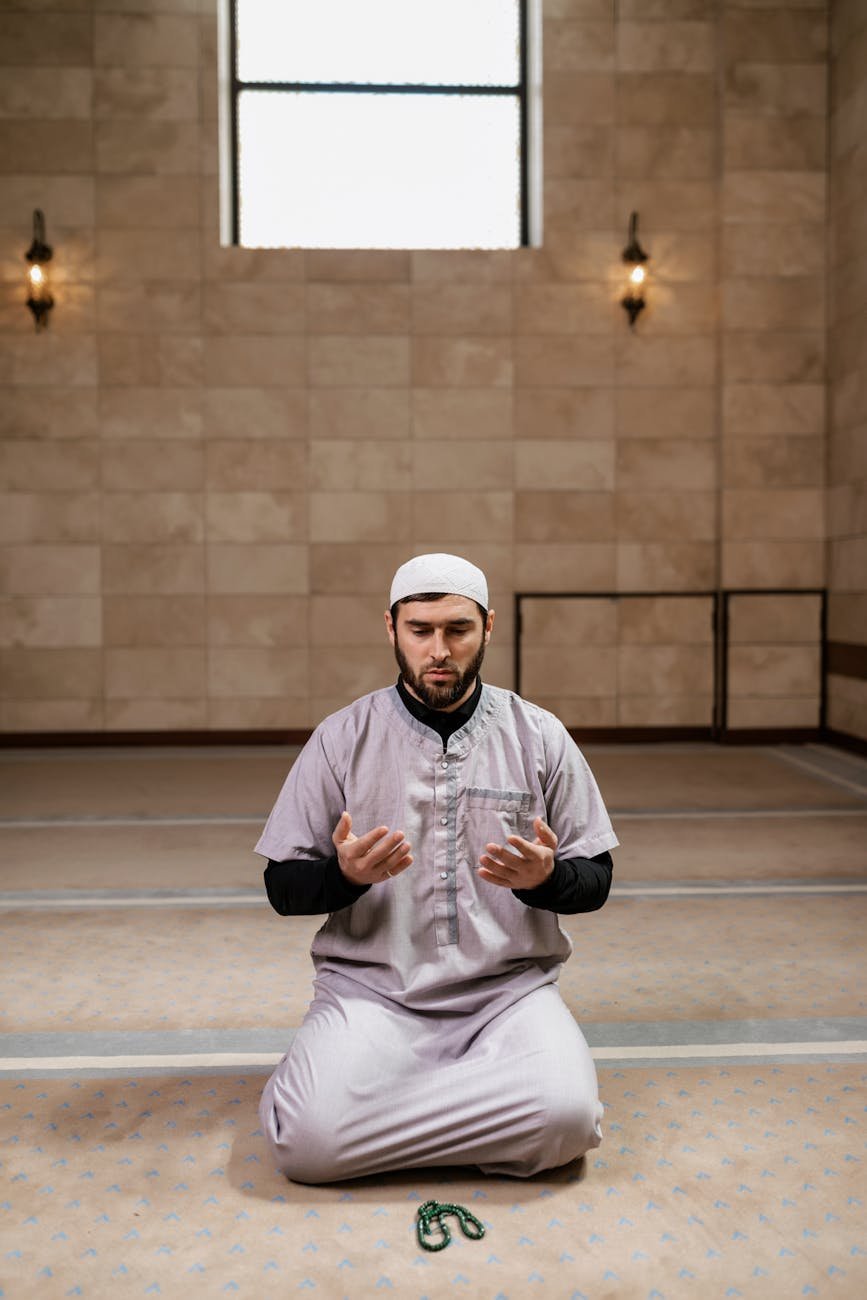 man in traditional clothing kneeling on the floor inside the mosque