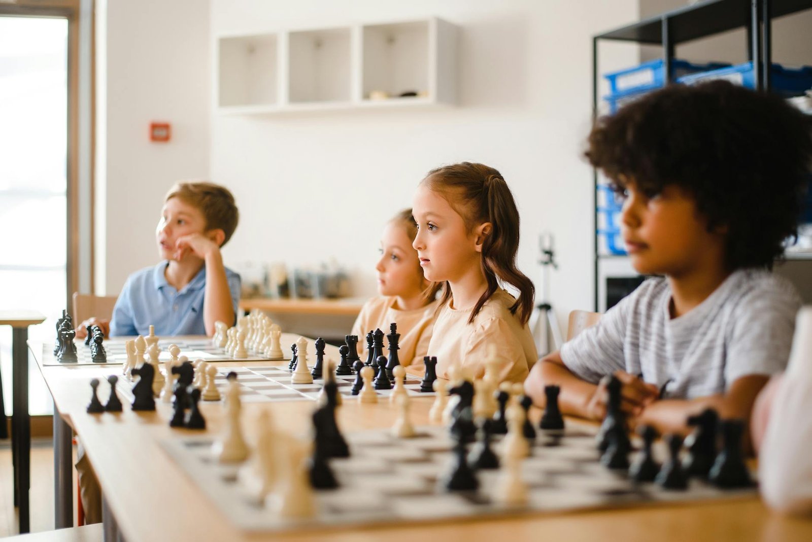boys and girls playing chess on table