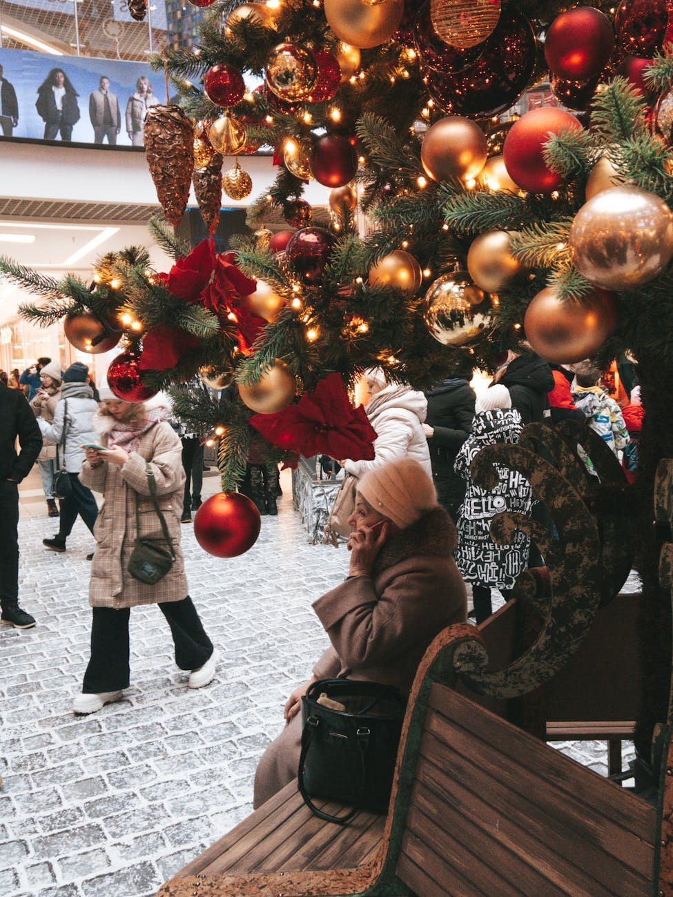 a person sitting on bench under a christmas tree