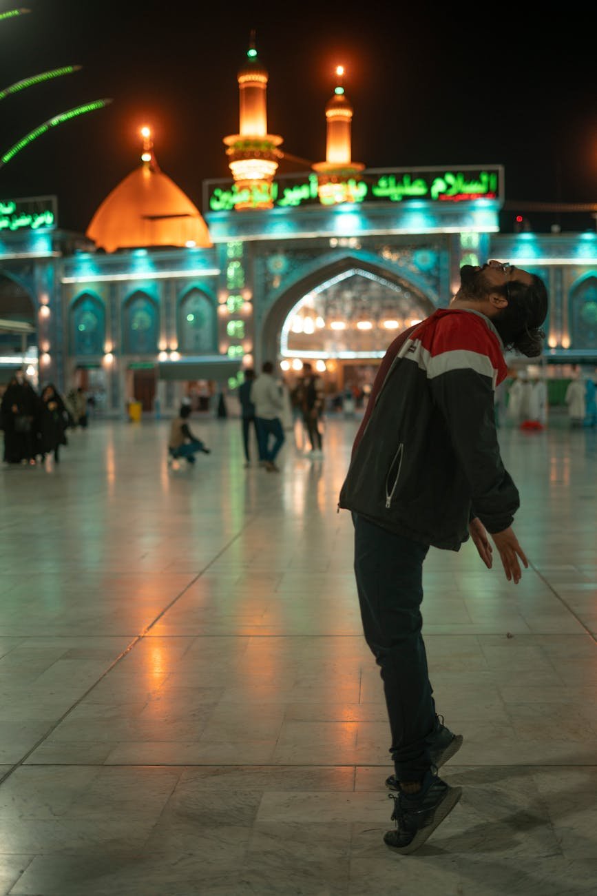 man posing in front of mosque at night