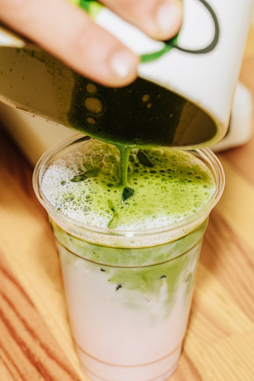 pouring matcha latte into a clear cup