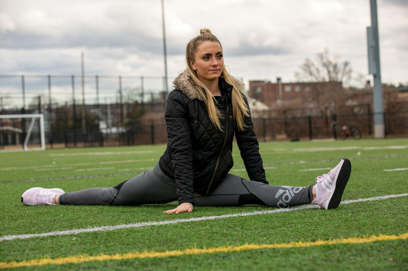 woman in black jacket and pants sitting on green grass field