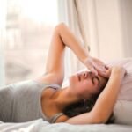 woman in gray tank top lying on bed