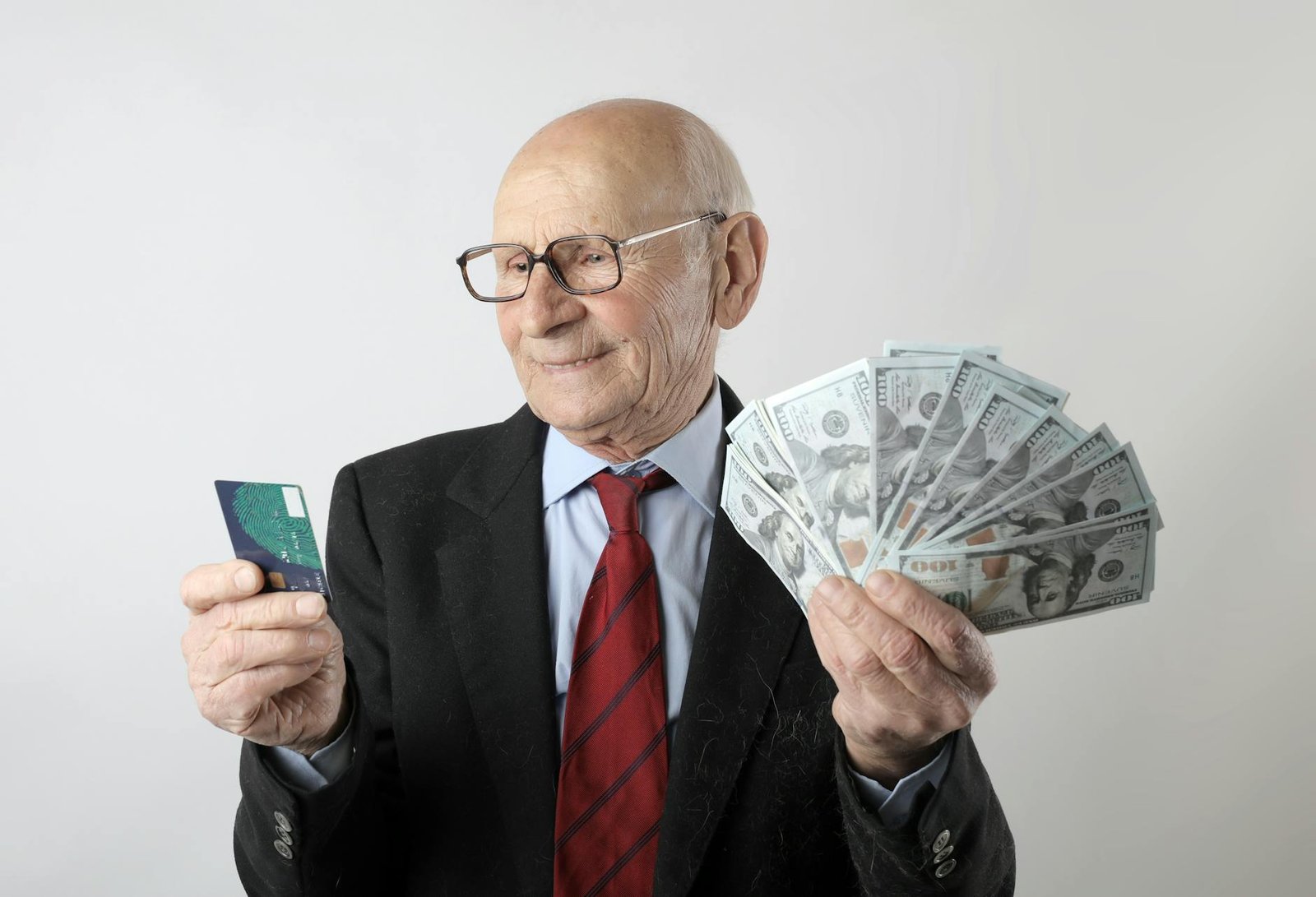 man in black suit holding banknotes and credit card