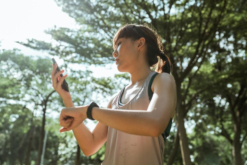 sporty sportswoman with smartphone and fitness bracelet in park