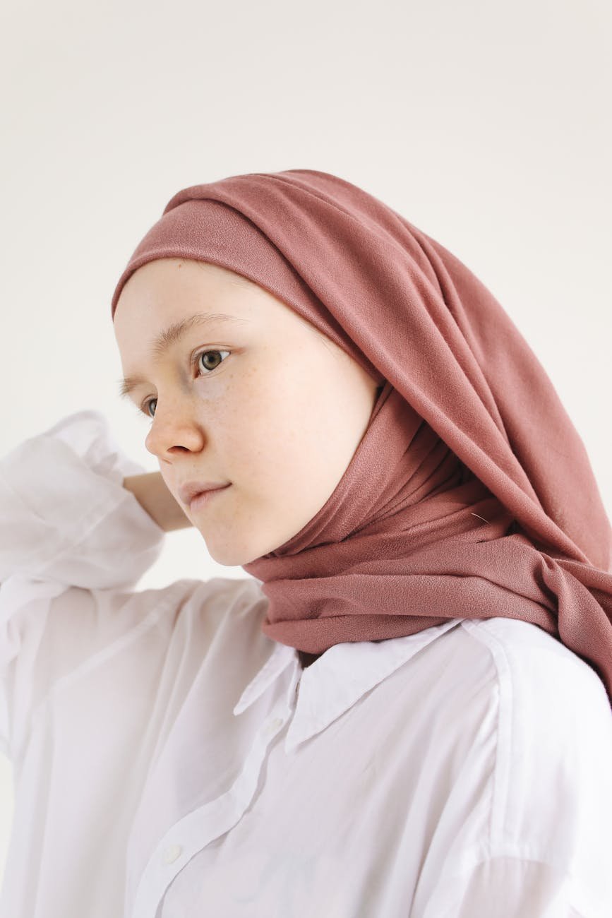 close up photo of a young woman posing in white long sleeve shirt and brown hijab