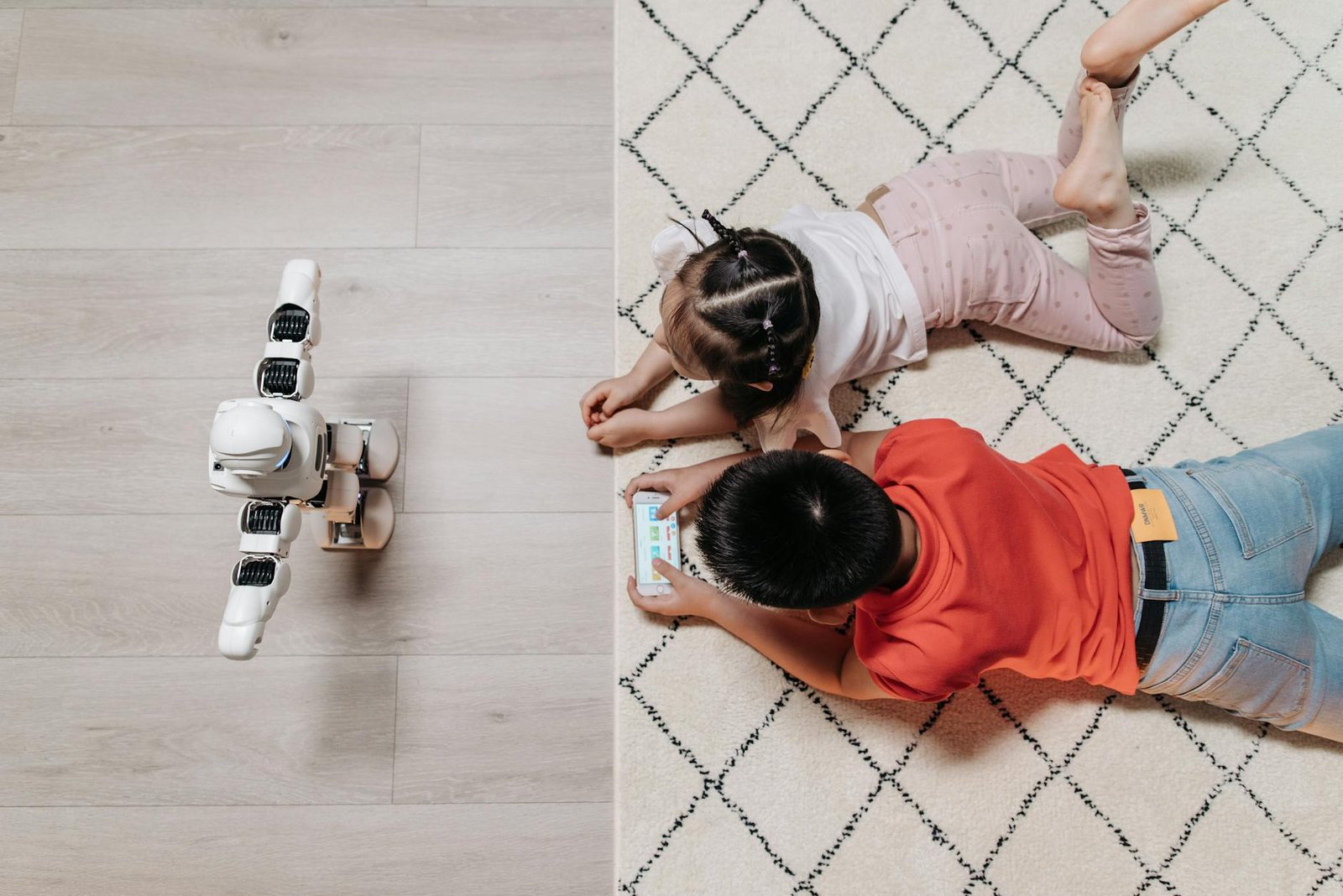 kids lying on the carpet in front of a robot