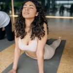 woman in beige brassiere and leggings stretching on the mat