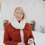 portrait of blonde woman in red jacket and scarf