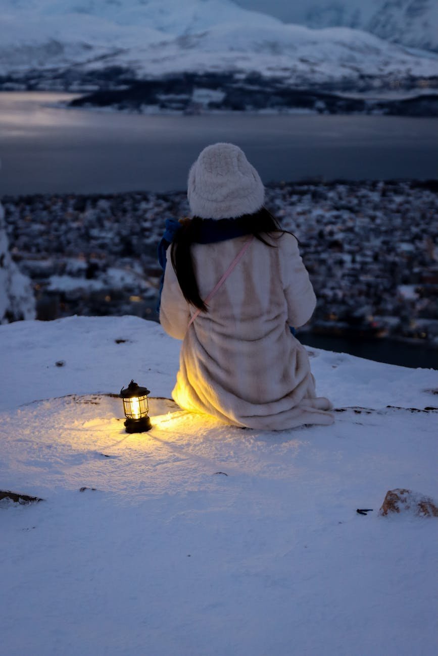 snowy view of tromso with lantern light