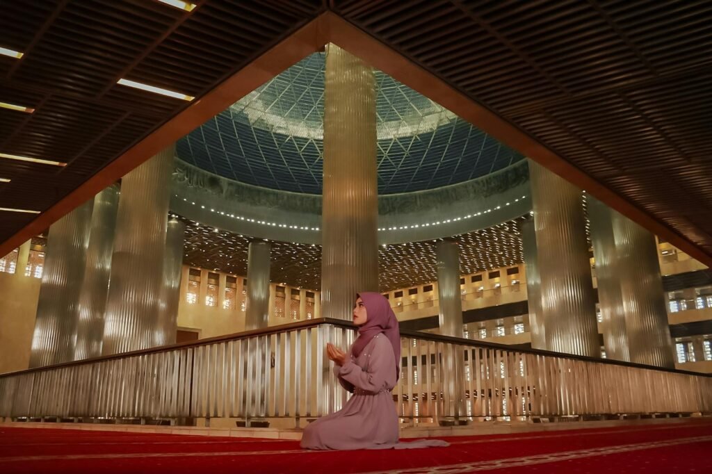 woman praying inside a grand mosque interior