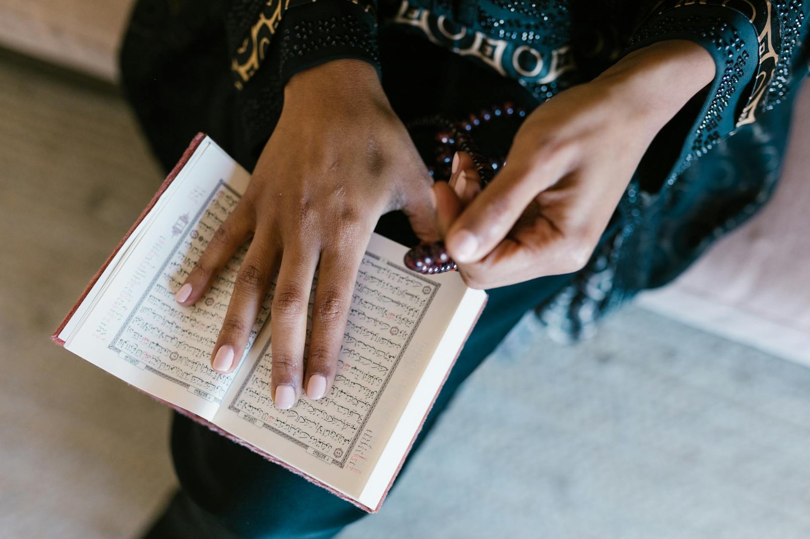 person in black and gold beaded bracelet holding book