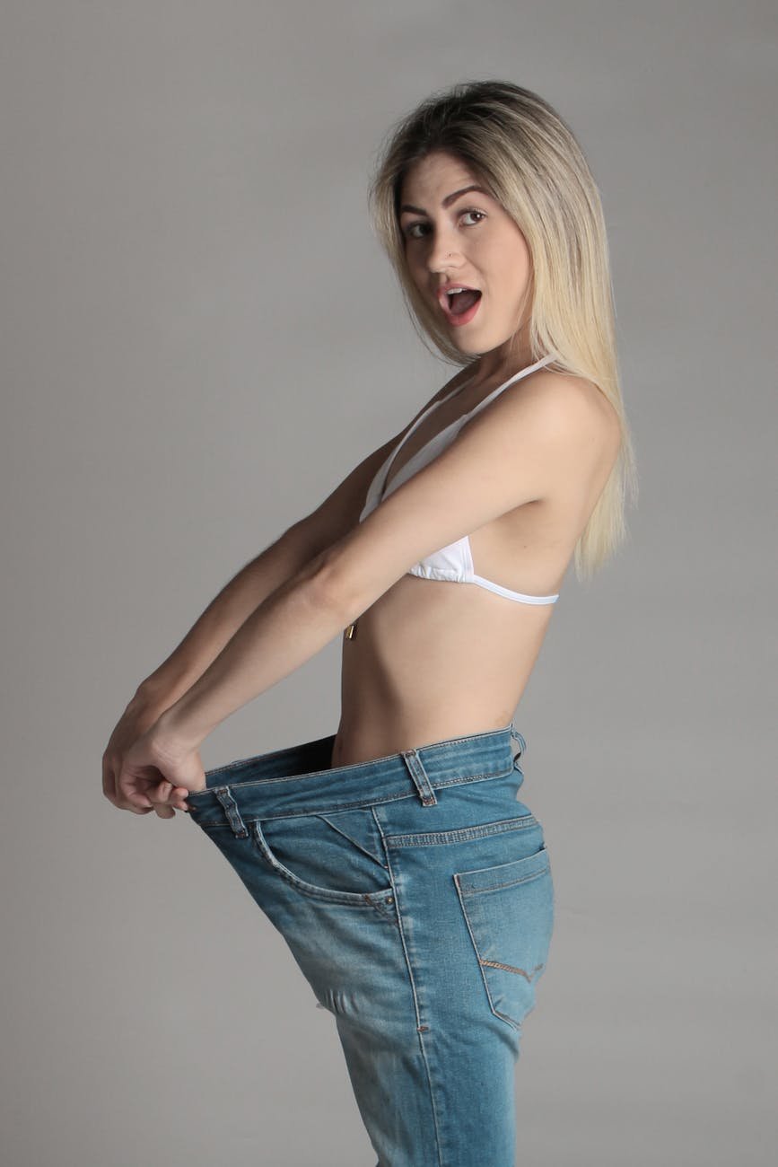 woman in white brassiere and blue denim pants