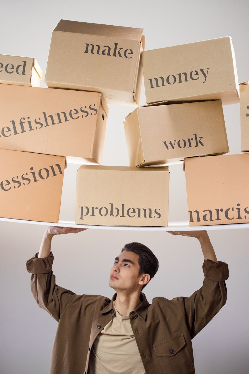 man in brown coat carrying a pile of cardboard boxes