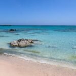 a clear water on the beach under the blue sky