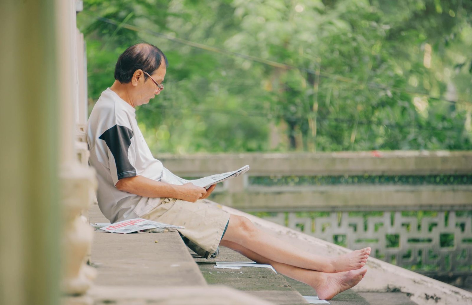 man sitting on staircase reading newspaper