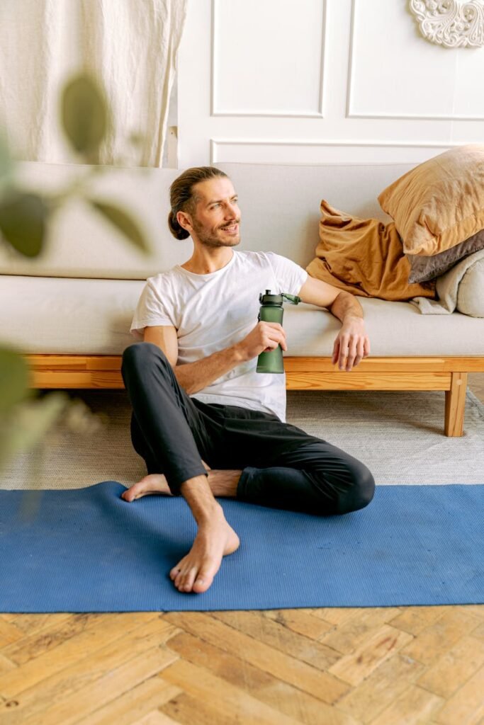 a man sitting on the floor while holding his water bottle