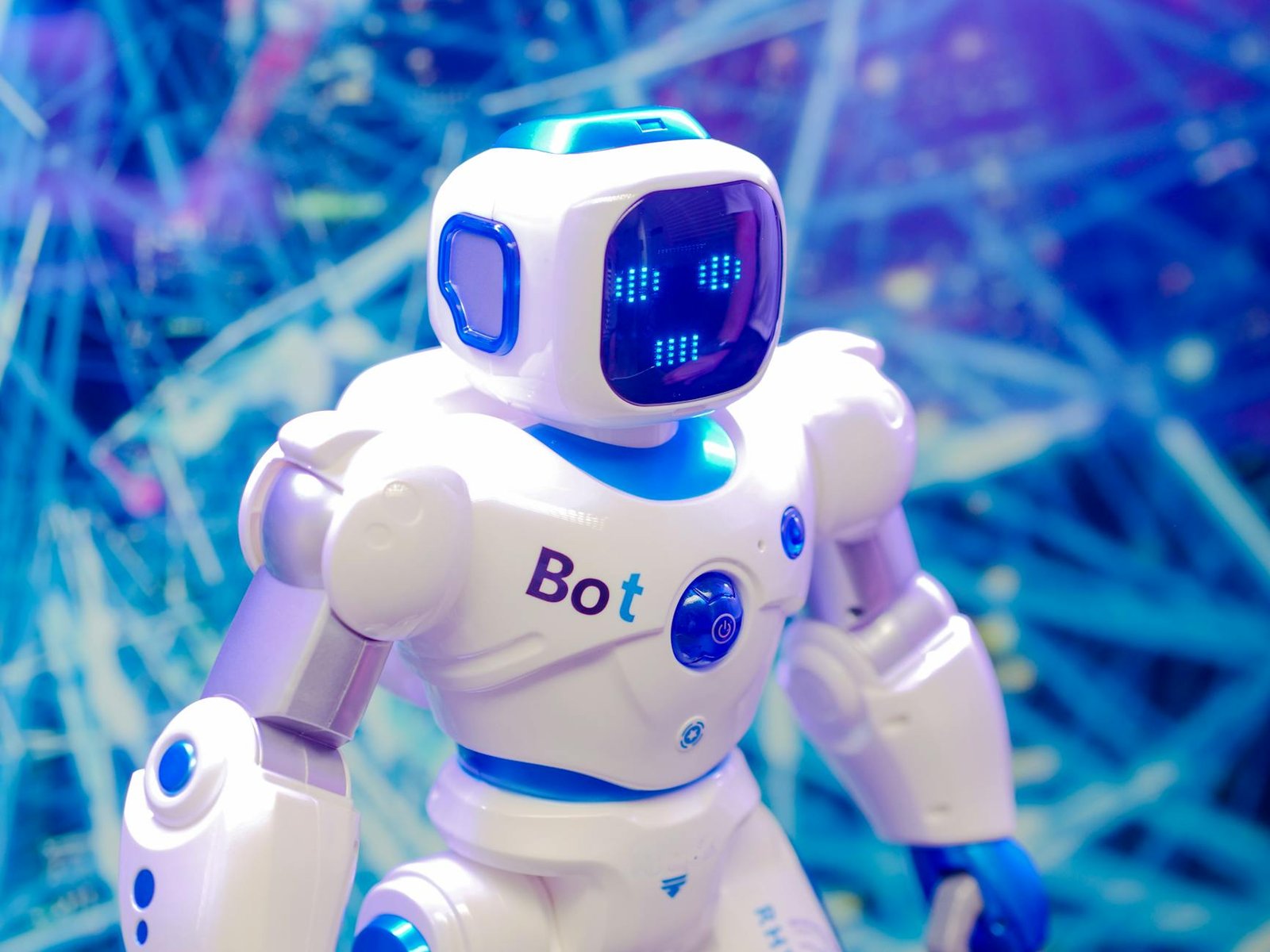 white and blue robot toy on blue string lights