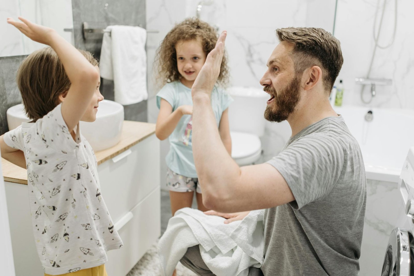 father giving high five to his son in a bathroom