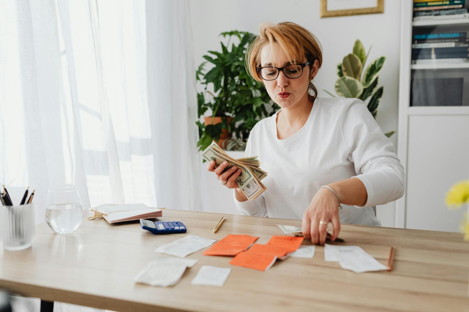 woman in white long sleeves sitting on the table counting money