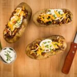 delicious loaded baked potatoes on wood surface