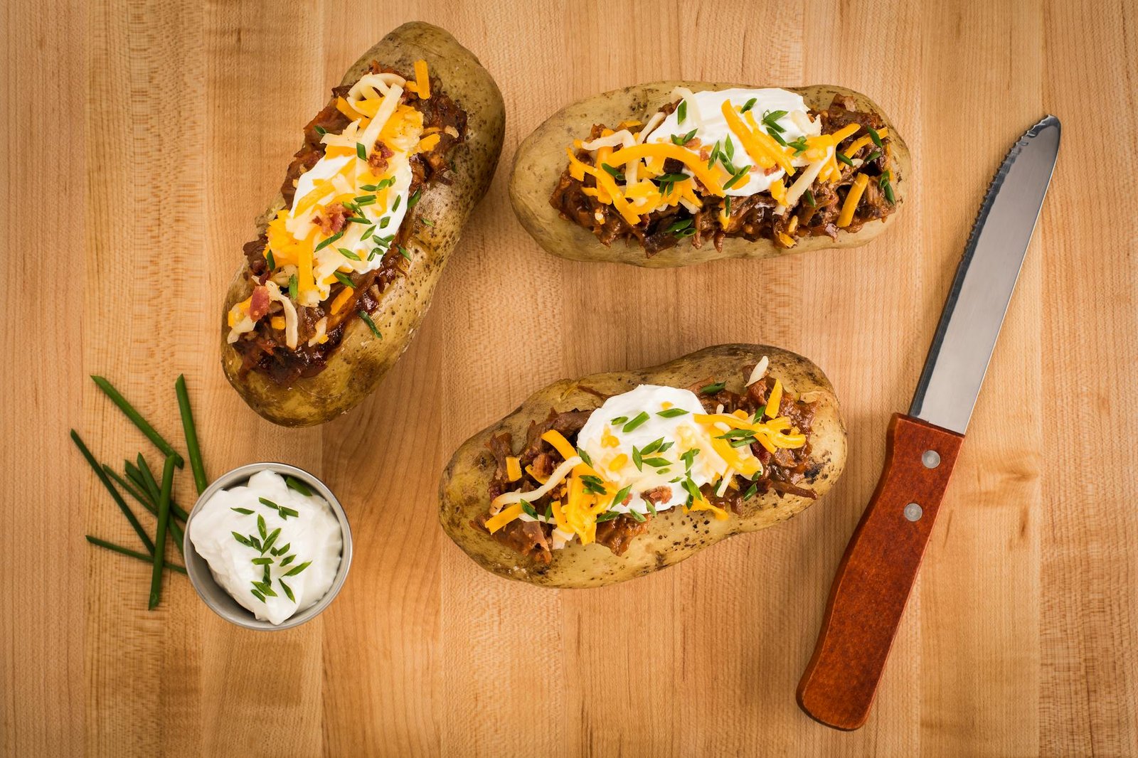 delicious loaded baked potatoes on wood surface