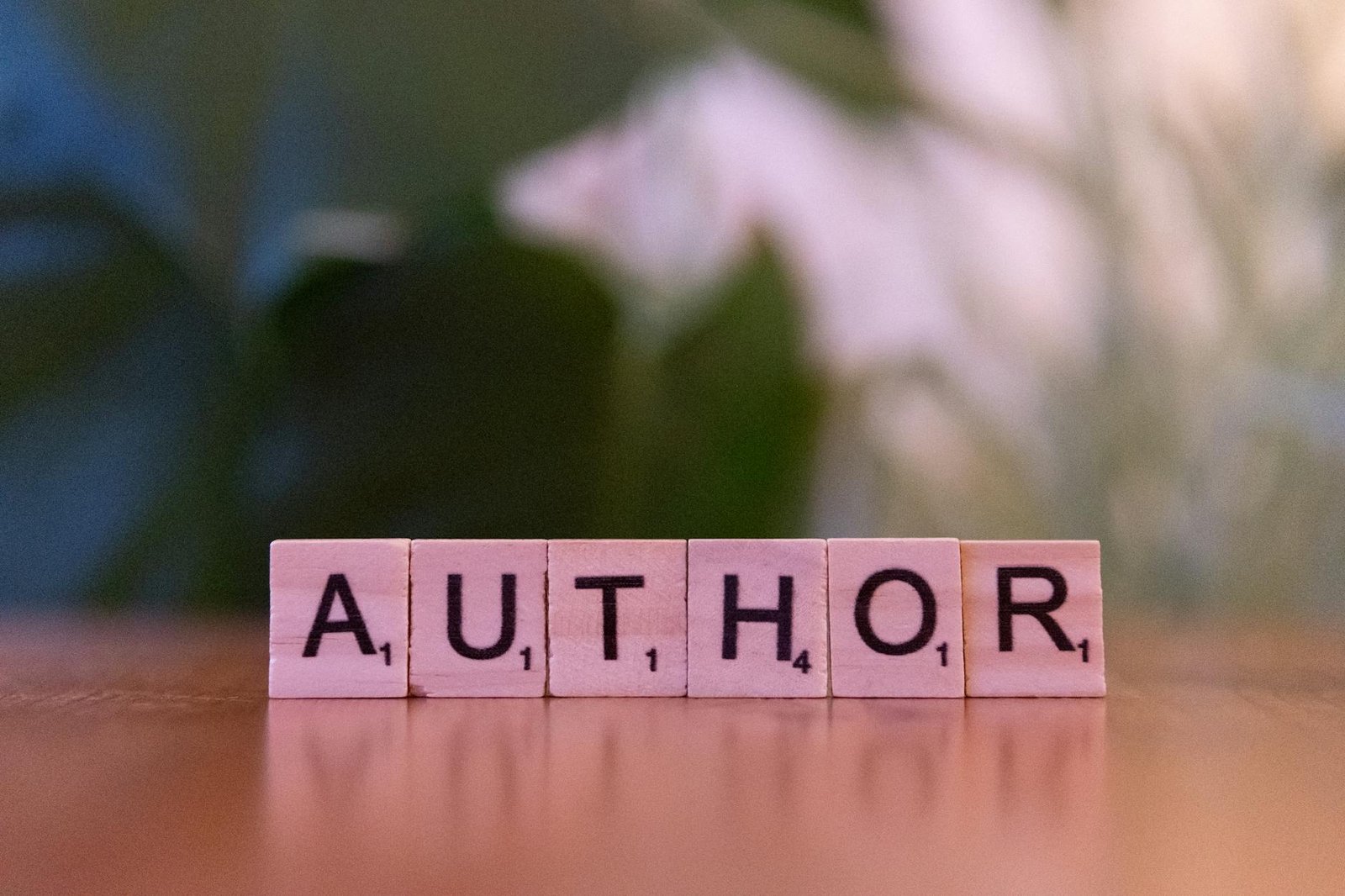 scrabble tiles spelling author on wooden surface