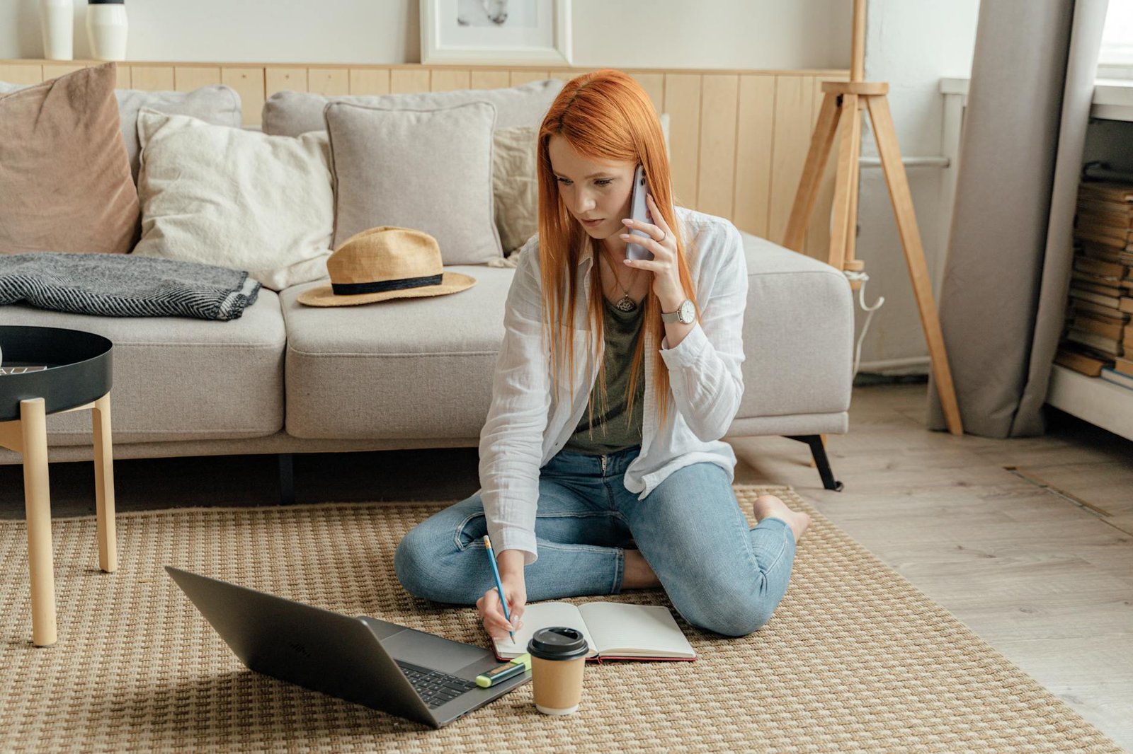 woman in white long sleeve shirt and blue denim jeans sitting on gray couch