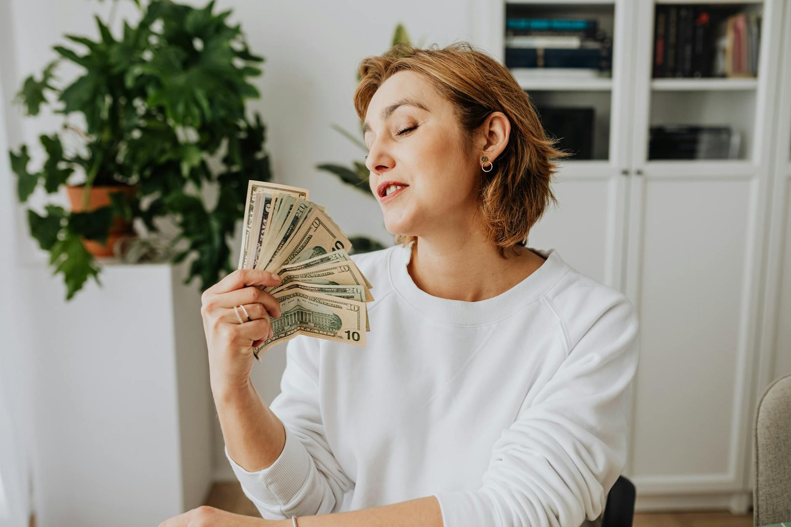 woman wearing a white sweater holding money